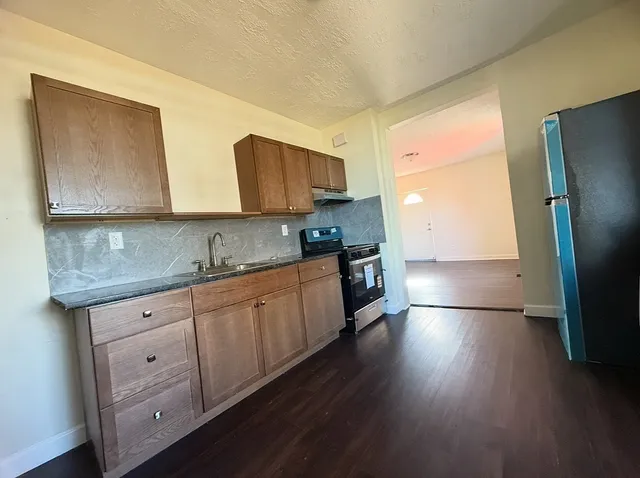 a kitchen with granite countertop a stove a sink and a refrigerator