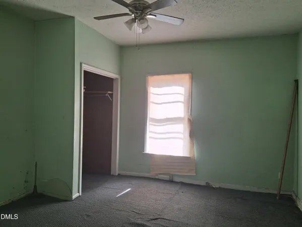 an empty room with a window and a ceiling fan