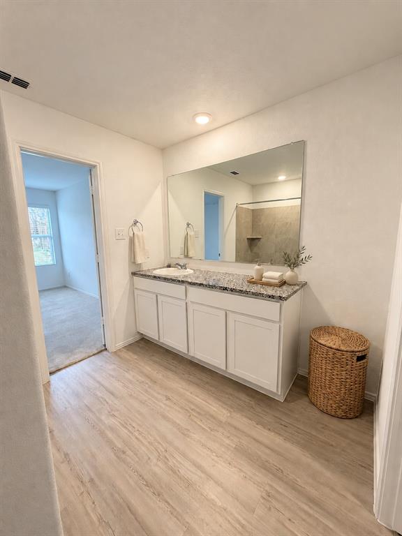 11726 Bone Spg Drive Rhome, TX 76078 - Photo 16 of 29 *Virtually Staged* En-suite primary bath featuring a granite countertop vanity, tiled tub and shower surround, recessed lighting, and luxury vinyl plank flooring.