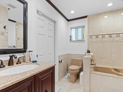 a bathroom with a granite countertop toilet a sink and a mirror