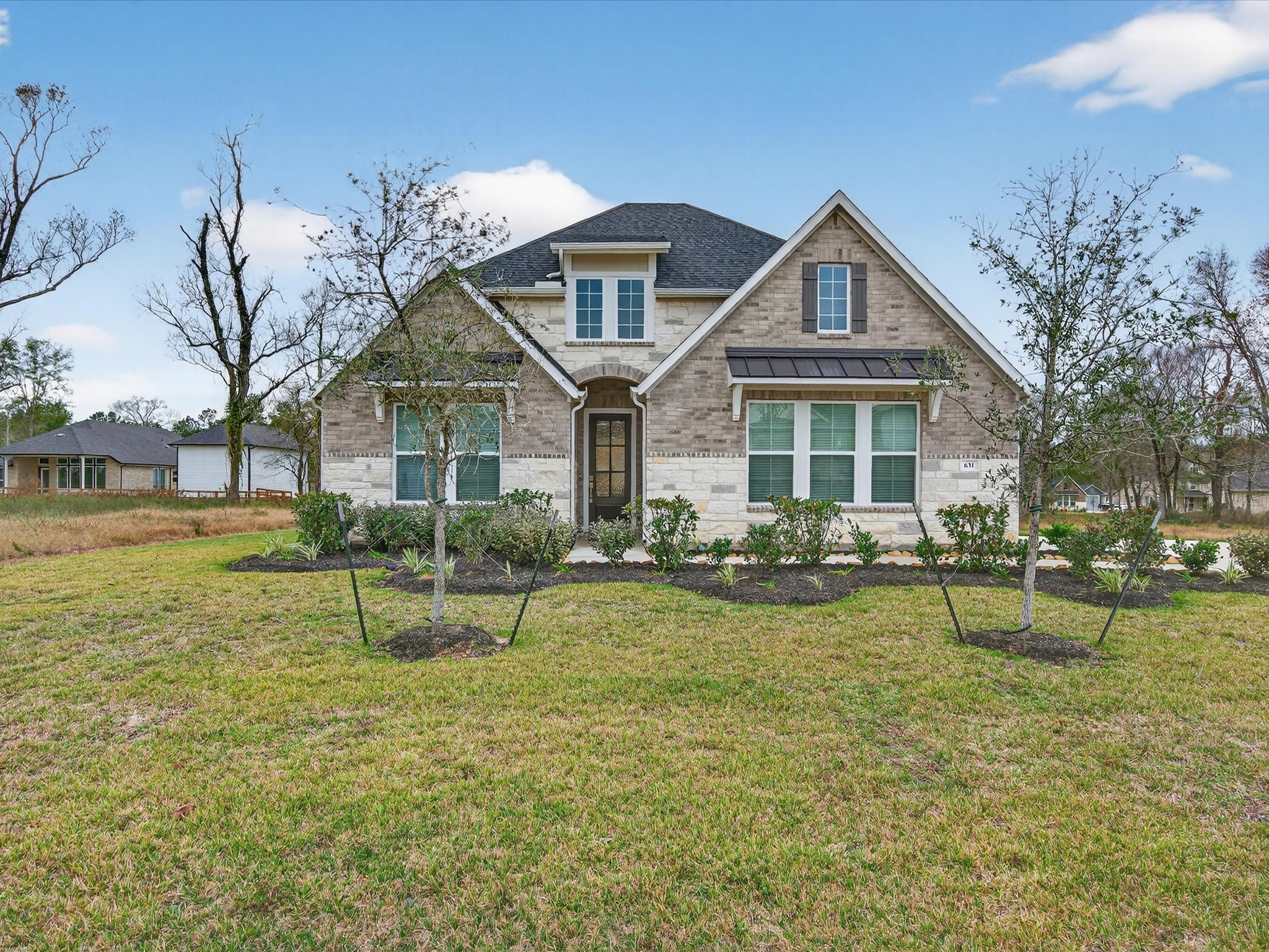 a front view of a house with garden and trees