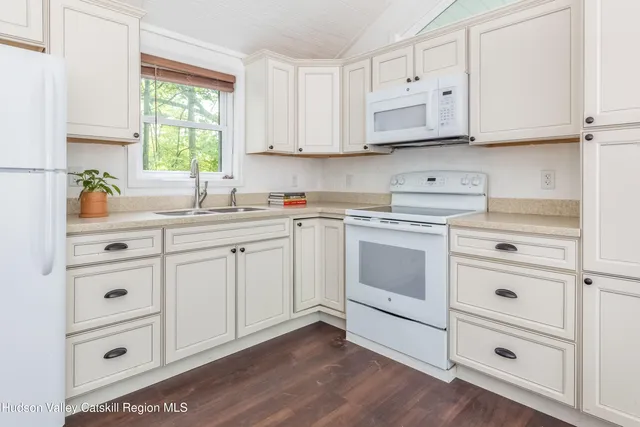a large white bed in a small room next to a window