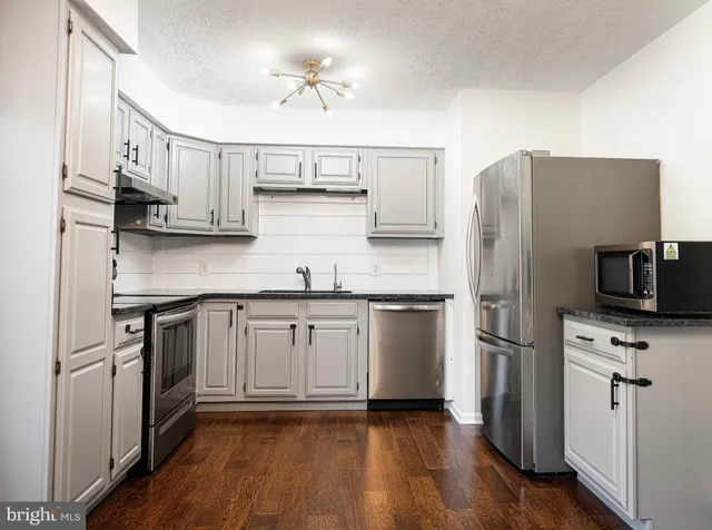 a kitchen with stainless steel appliances a stove top oven a sink and a refrigerator