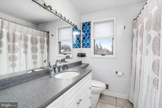 a bathroom with a granite countertop sink mirror vanity and toilet