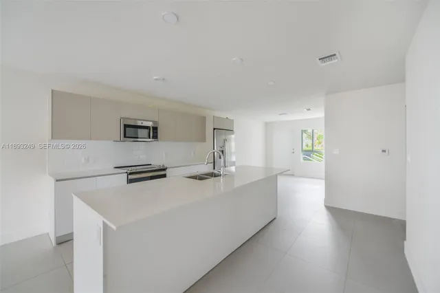 a living room with stainless steel appliances a sink a counter top space and cabinets
