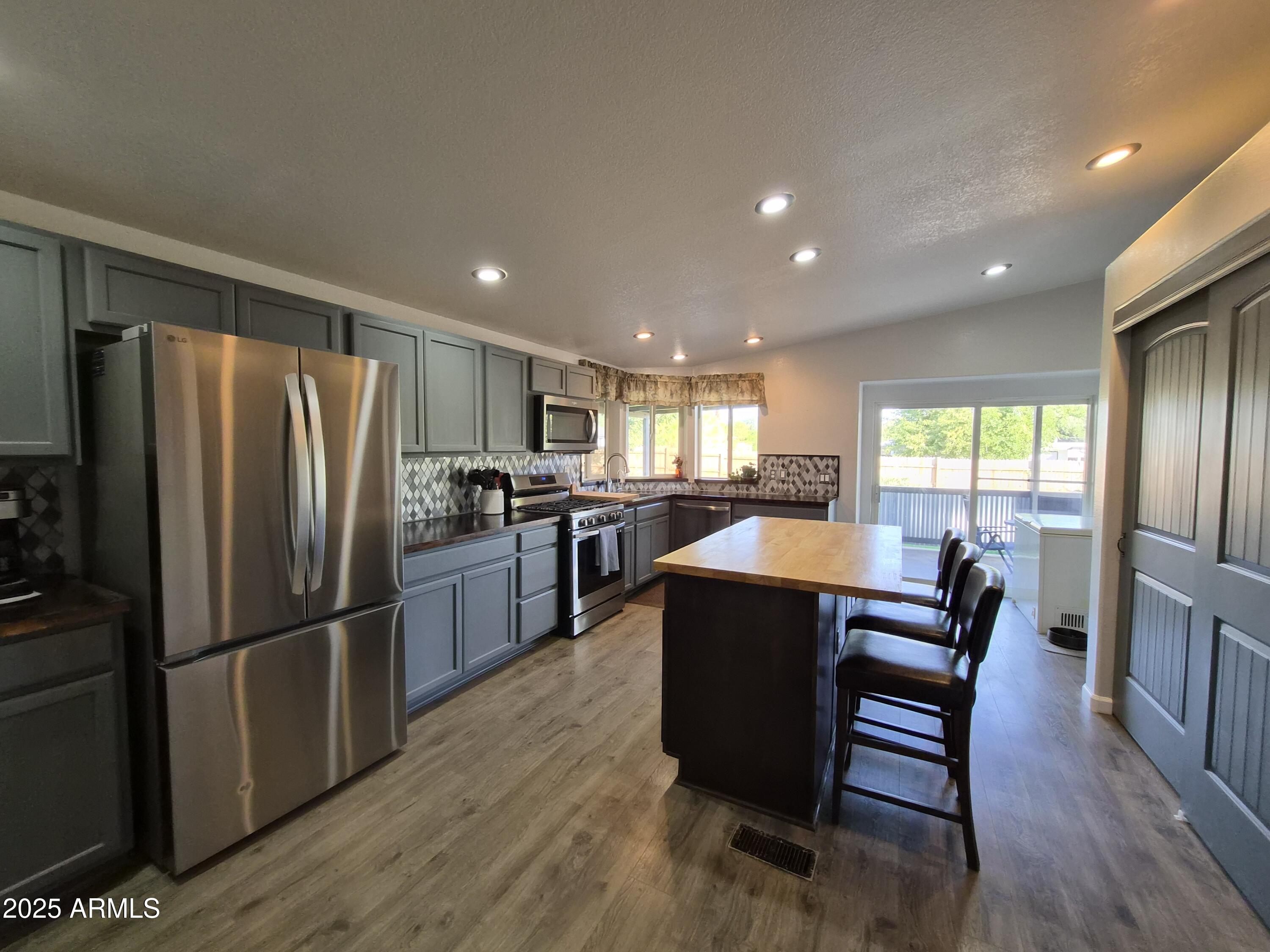 51033 North Mockingbird Road Wickenburg, AZ 85390 - Photo 11 of 51 a kitchen with stainless steel appliances granite countertop a refrigerator a sink dishwasher a stove and a refrigerator with wooden floor