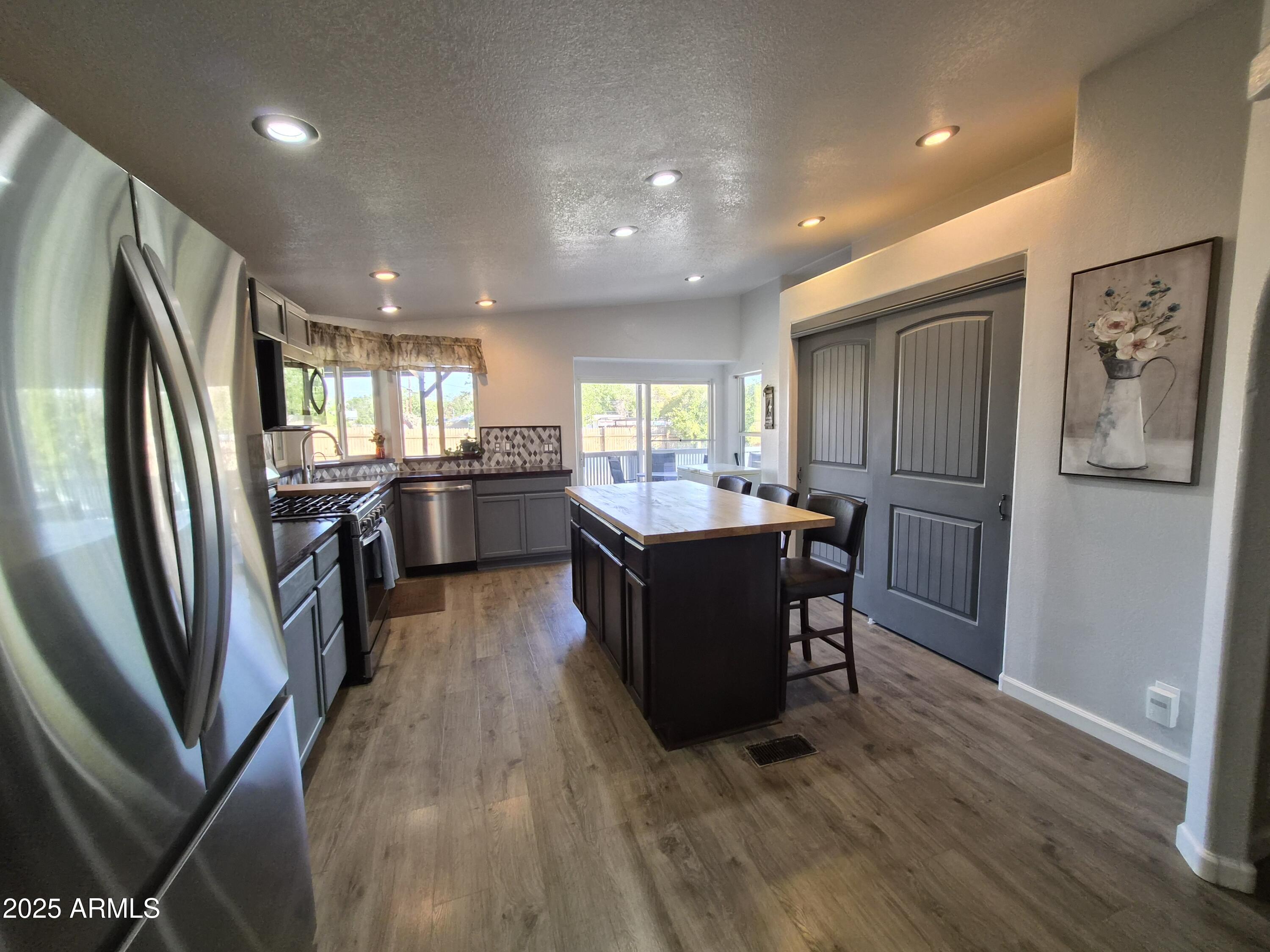 51033 North Mockingbird Road Wickenburg, AZ 85390 - Photo 10 of 51 a kitchen with stainless steel appliances granite countertop a refrigerator a sink dishwasher a stove and a dining table with wooden floor