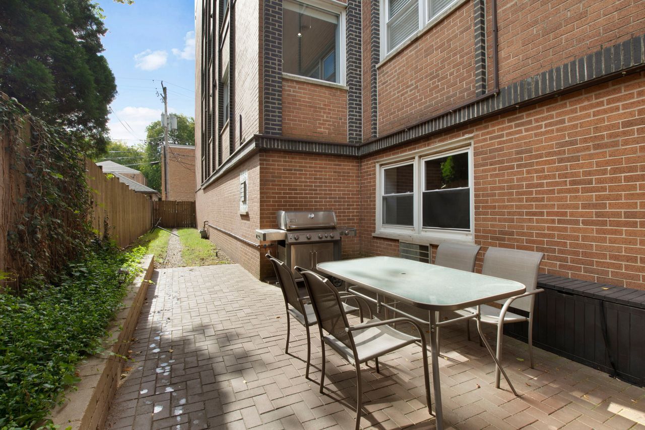 612 Mulford Street, Unit 203 Evanston, IL 60202 - Photo 18 of 19 a backyard of a house with table and chairs