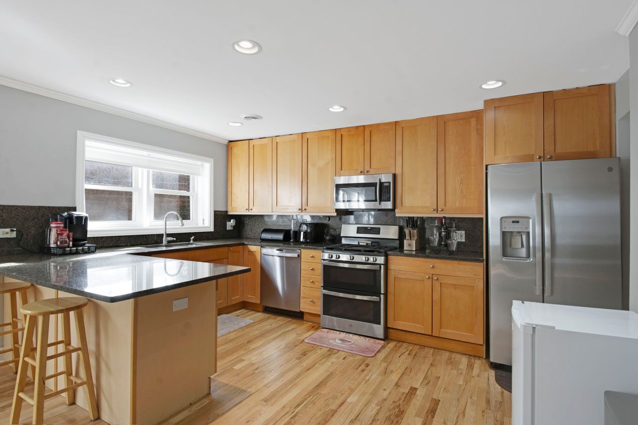 612 Mulford Street, Unit 203 Evanston, IL 60202 - Photo 5 of 19 a kitchen with stainless steel appliances granite countertop a stove a sink dishwasher a refrigerator and a microwave oven with wooden floor
