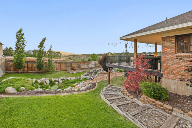 2342 Charros Road Sandy, UT 84092 - Photo 88 of 94 Expansive backyard featuring a manicured lawn, a stone pathway, decorative rock landscaping, and mature trees