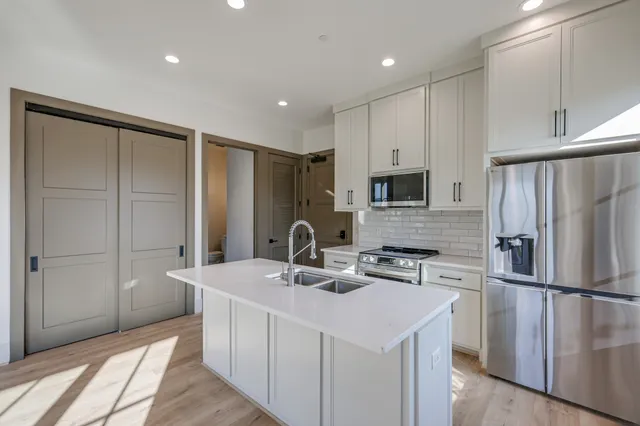 a kitchen with kitchen island a sink stainless steel appliances and refrigerator