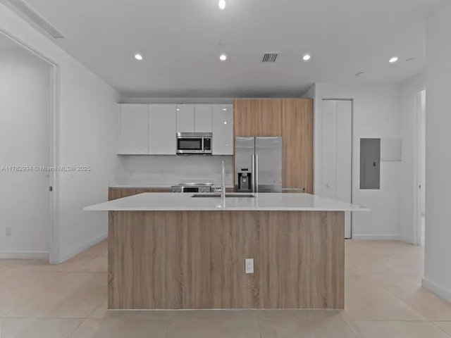 a kitchen with kitchen island granite countertop a sink stove and cabinets