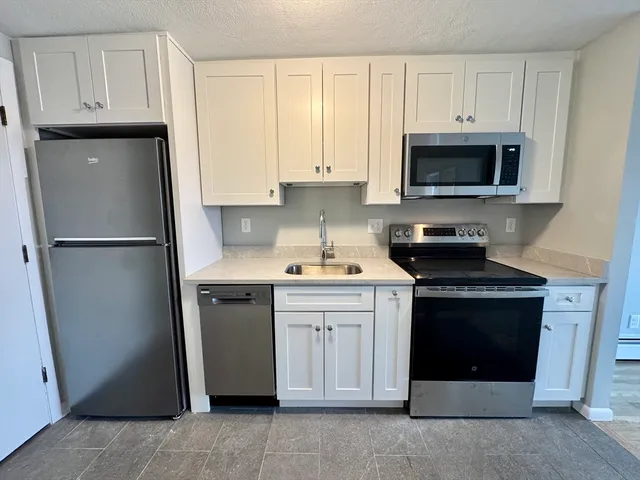 a kitchen with stainless steel appliances granite countertop a refrigerator stove and sink