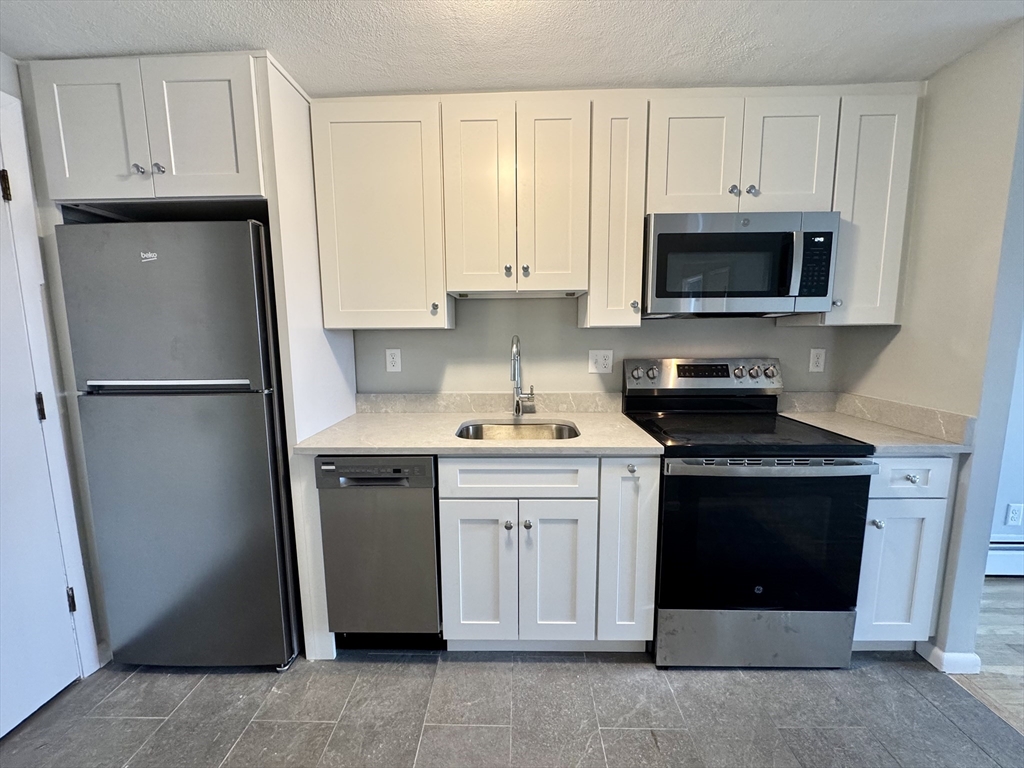 97 Spring Street, Unit C2 Boston, MA 02132 - Photo 1 of 11 a kitchen with stainless steel appliances granite countertop a refrigerator stove and sink