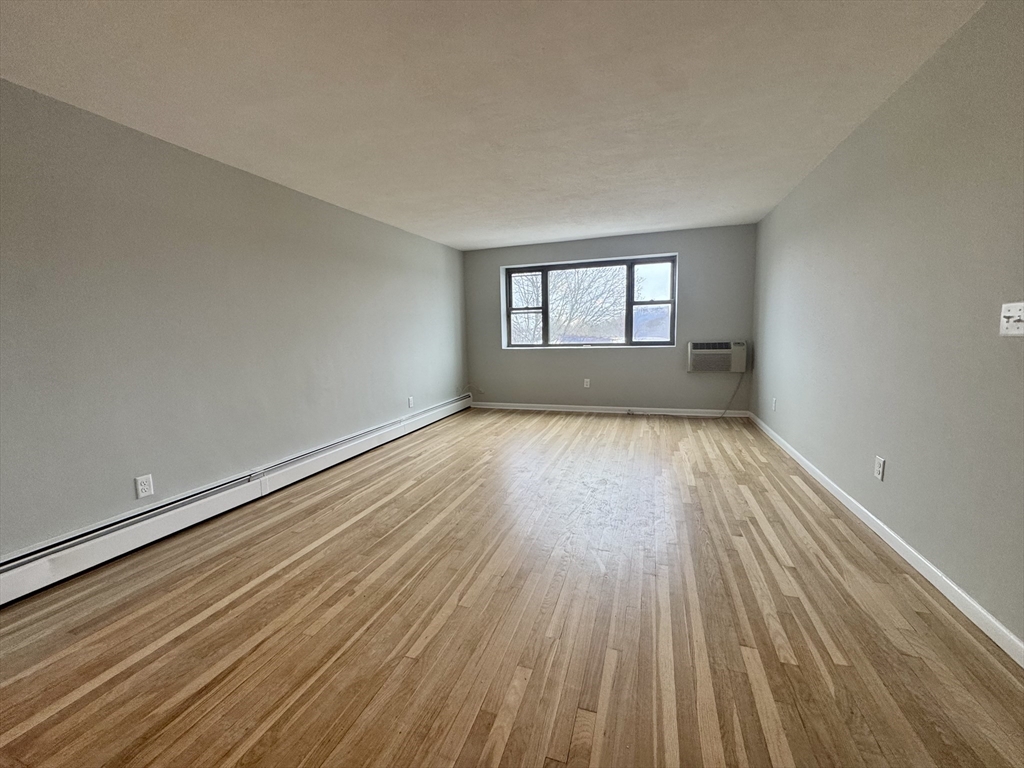 97 Spring Street, Unit C2 Boston, MA 02132 - Photo 2 of 11 wooden floor in an empty room with a window