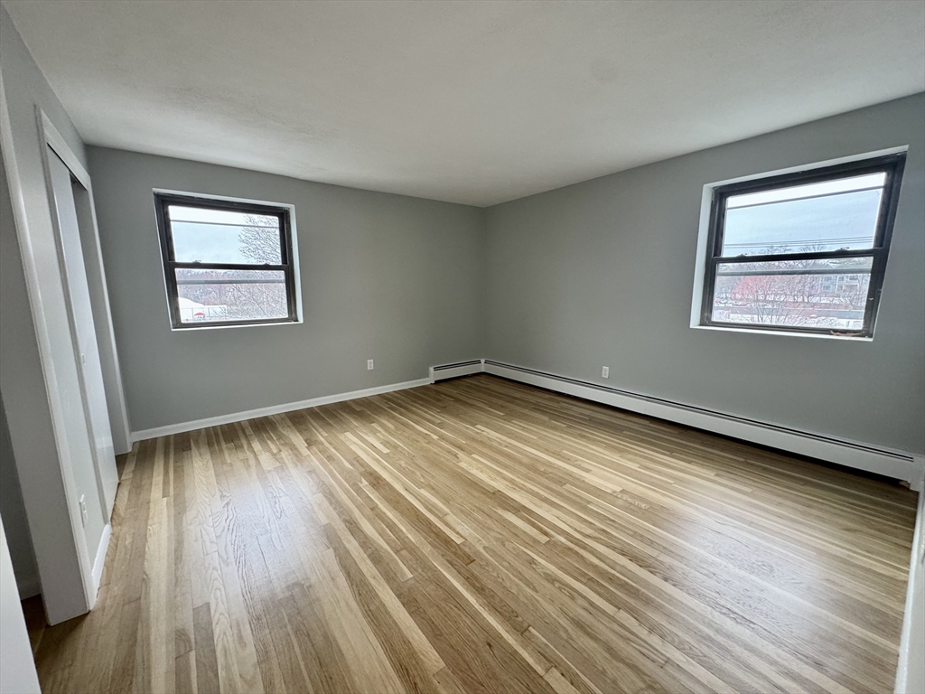 97 Spring Street, Unit C2 Boston, MA 02132 - Photo 5 of 11 a view of an empty room with wooden floor and a window
