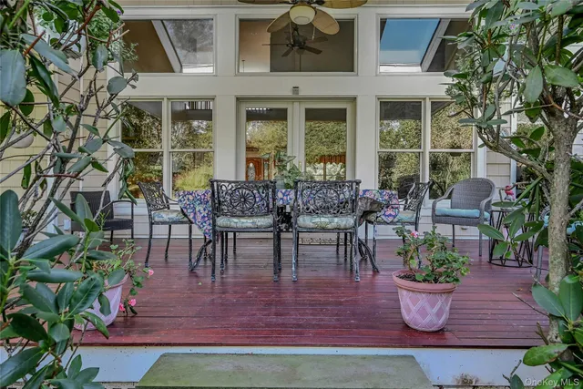 a view of a backyard with table and chairs potted plants and a large tree