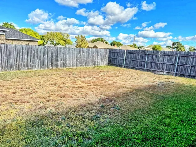 a view of a backyard with wooden fence