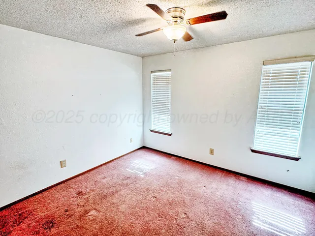 an empty room with a window and a ceiling fan