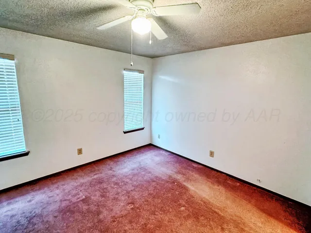 an empty room with a ceiling fan and a window