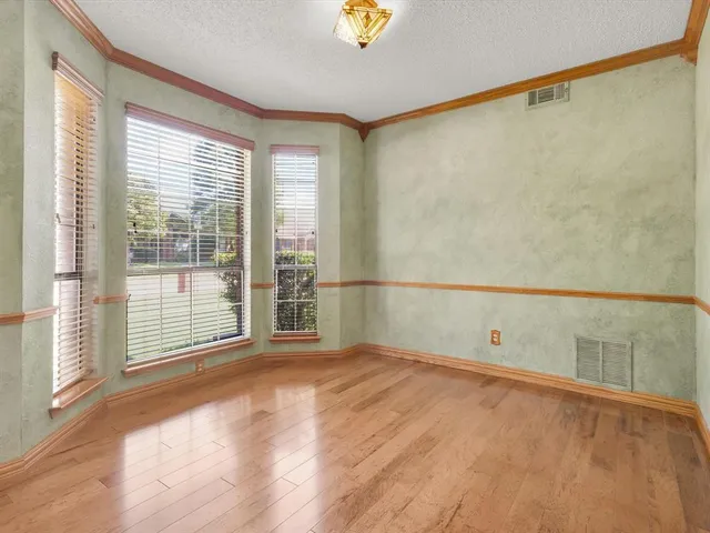 a view of an empty room with wooden floor and a fireplace