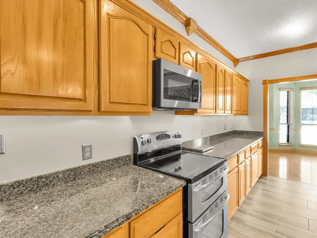 a view of an empty room with a window and a kitchen