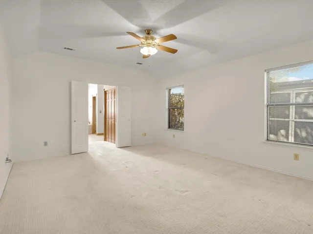 an empty room with windows and fan