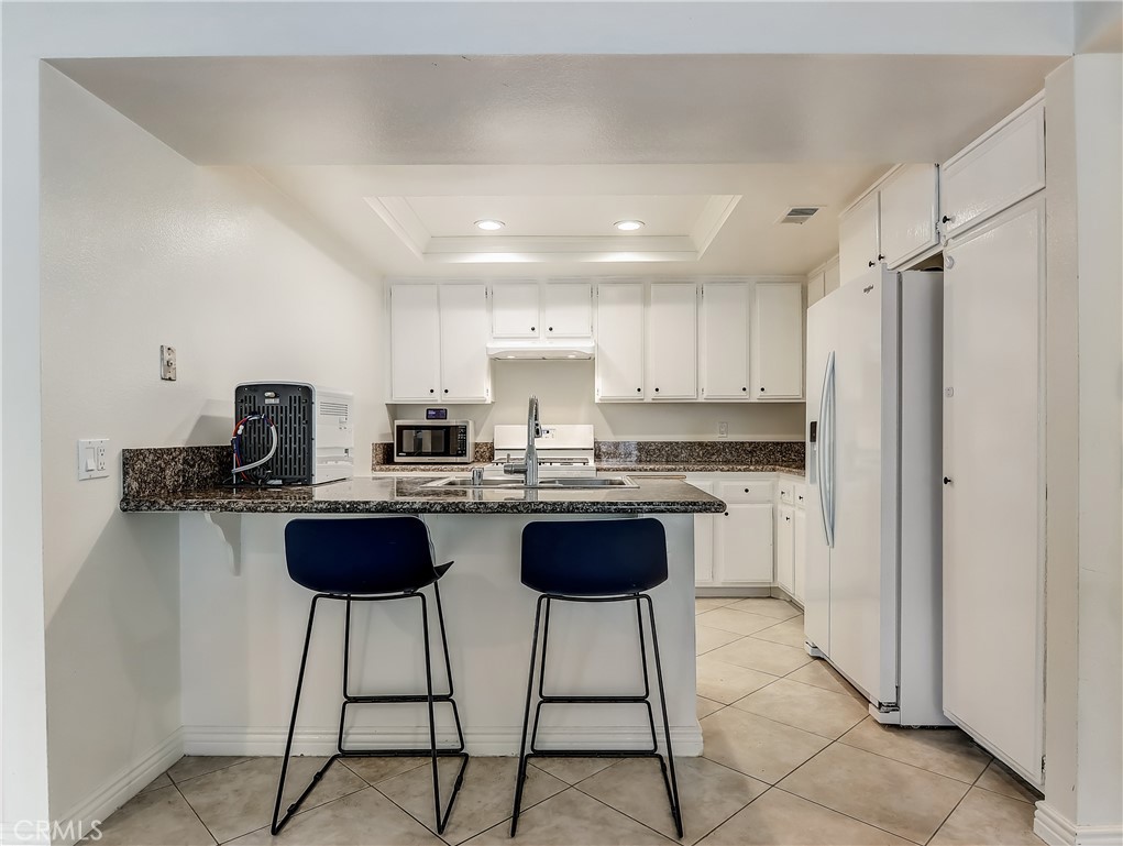 98 Greenfield, Unit 95 Irvine, CA 92614 - Photo 11 of 48 a kitchen with a dining table chairs and a refrigerator