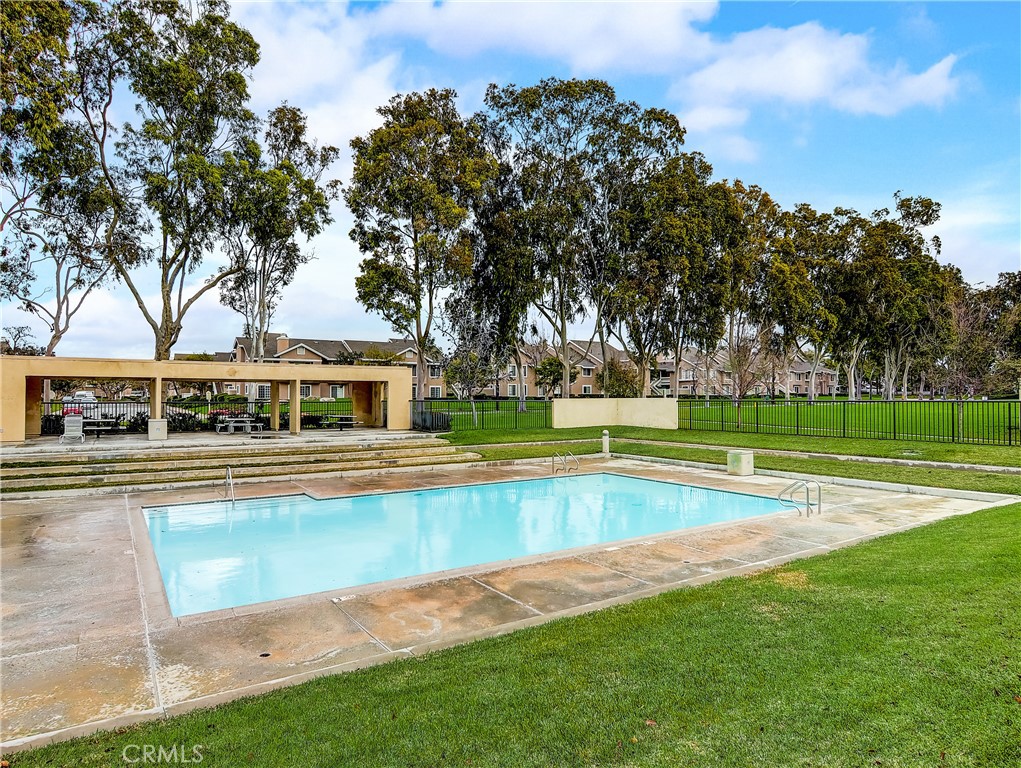 98 Greenfield, Unit 95 Irvine, CA 92614 - Photo 45 of 48 a view of a swimming pool with lawn chairs under an umbrella