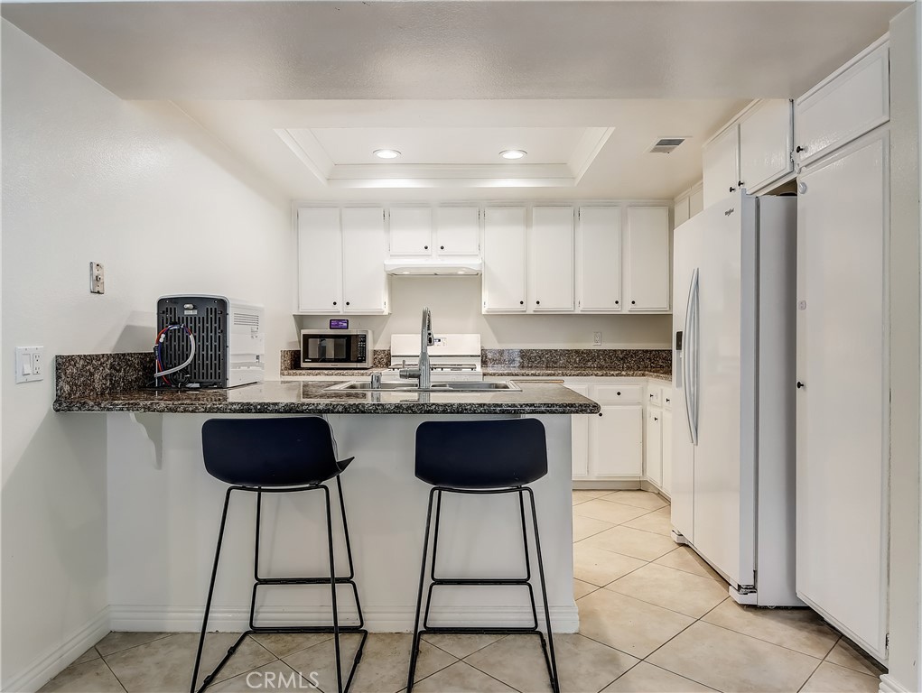 98 Greenfield, Unit 95 Irvine, CA 92614 - Photo 10 of 48 a kitchen with stainless steel appliances granite countertop a refrigerator and a stove top oven