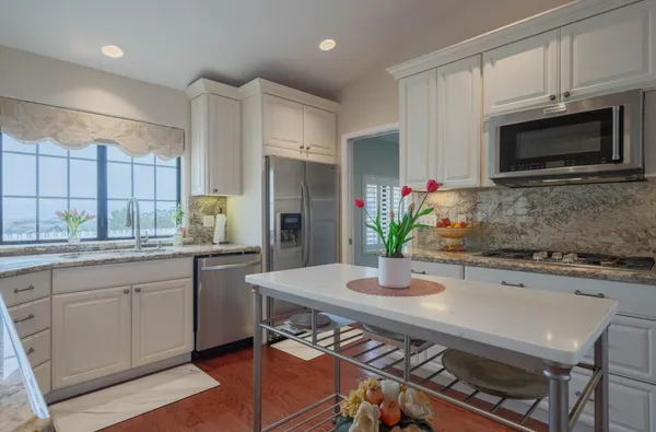 a kitchen with stainless steel appliances a sink a stove a microwave a refrigerator and cabinets
