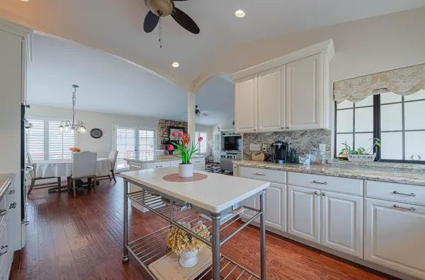 a kitchen with stainless steel appliances granite countertop a stove top oven a sink a dining table and chairs with wooden floor