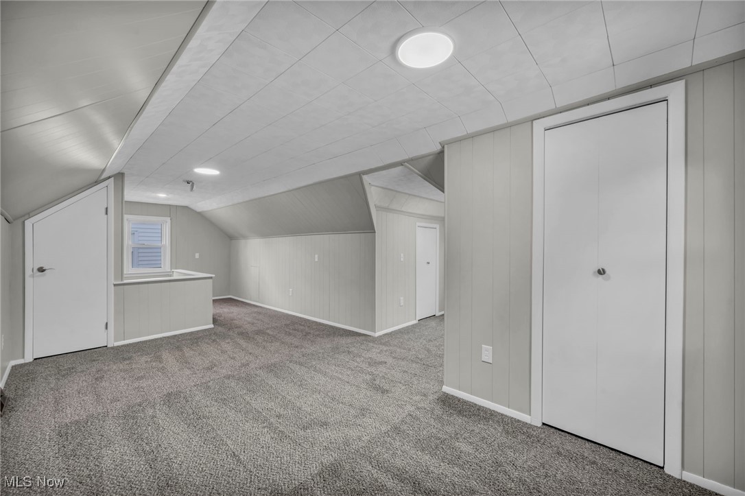 1560 Douglas Road Wickliffe, OH 44092 - Photo 27 of 39 Additional living space with carpet, wood walls, and lofted ceiling