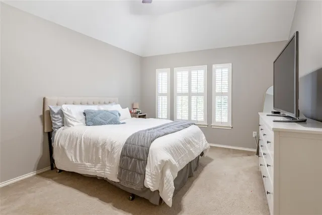 a bedroom with a bed table flat screen tv and a window