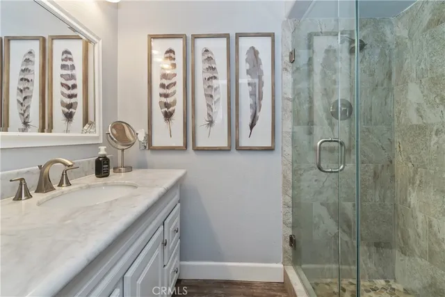 a bathroom with a granite countertop sink a mirror a vanity and shower