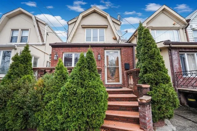 a view of a white house with large windows and a small yard