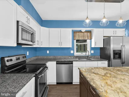 a kitchen with granite countertop a sink and white cabinets