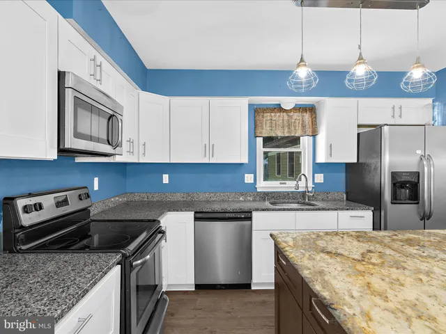 a kitchen with granite countertop a sink and white cabinets