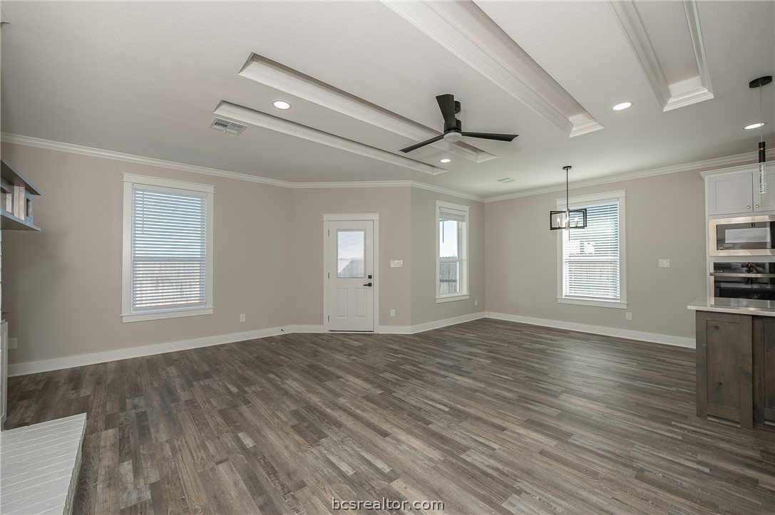 2908 GOLDBERG Drive Bryan, TX 77808 - Photo 28 of 44 View of the family room into the kitchen and dining area, window treatments, decorative cove lighting, ceiling fan with lite kit, can lights, gas fireplace, and wood mantle, floating shelves, pop up ceilings and vinyl flooring.