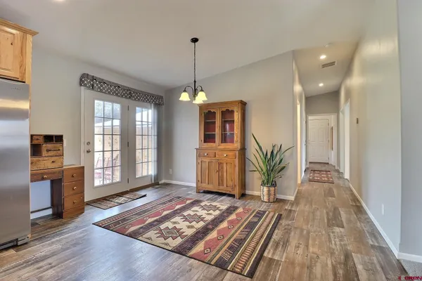 a view of a hallway with wooden floor windows a chandelier and a living room
