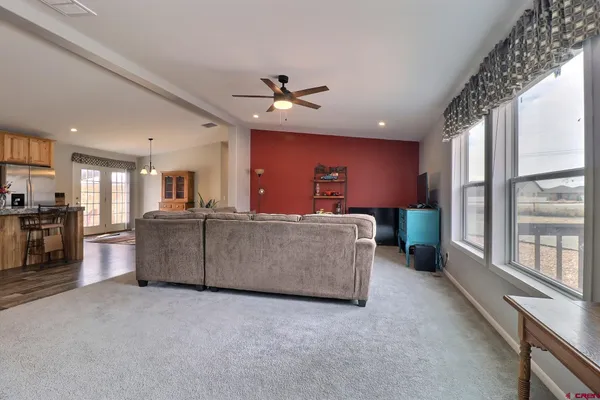 a living room with furniture a ceiling fan and a kitchen