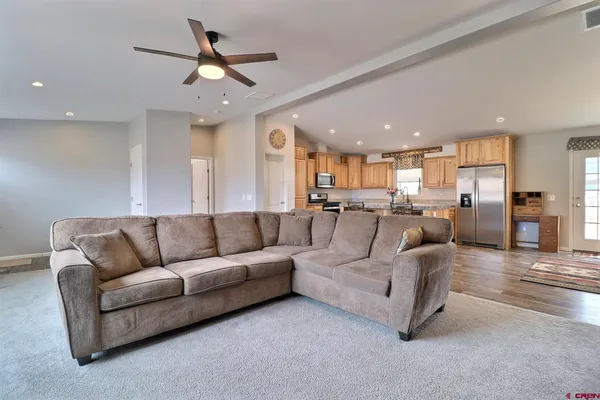 a living room with furniture kitchen view and a chandelier