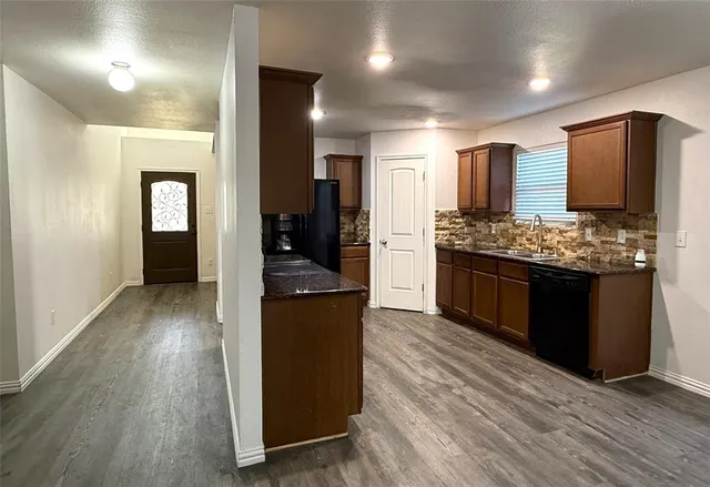 a kitchen with stainless steel appliances kitchen island granite countertop wooden floors and sink