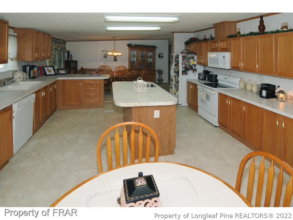 5117 Maxwell Road Stedman, NC 28391 - Photo 4 of 20 a kitchen with stainless steel appliances wooden cabinets a sink and a stove