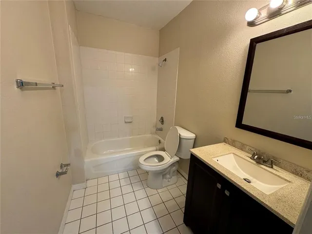 a bathroom with a granite countertop toilet a sink a mirror a bathtub and shower