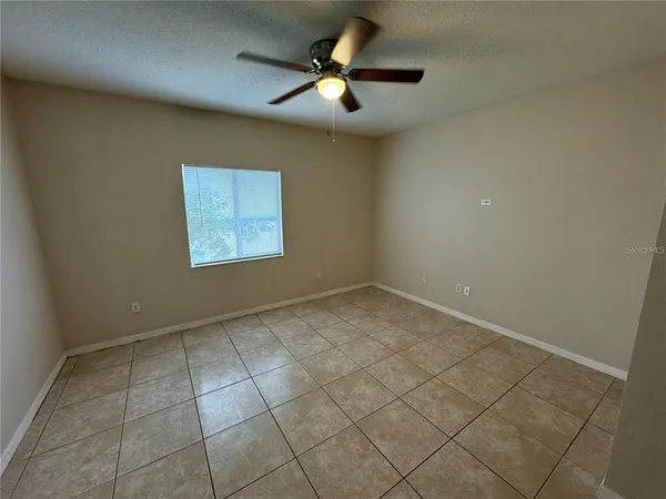 an empty room with a ceiling fan and window