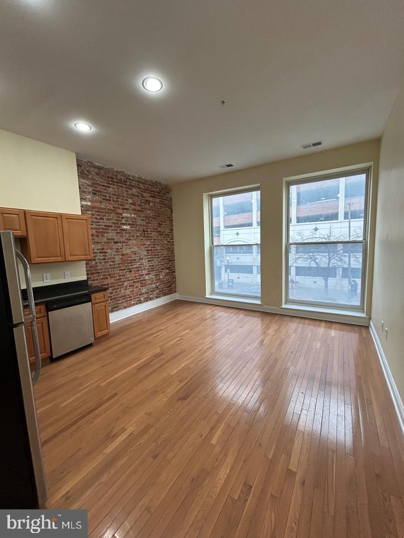 106 North Eutaw Street, Unit 3A Baltimore, MD 21201 - Photo 3 of 6 an empty room with wooden floor fireplace and windows