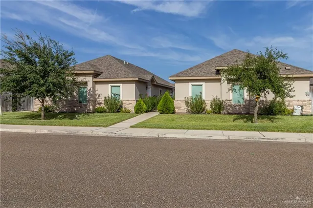 a view of a house with a big yard plants and palm trees