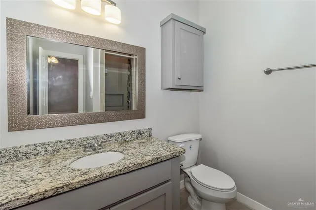 a bathroom with a granite countertop toilet a sink and a mirror