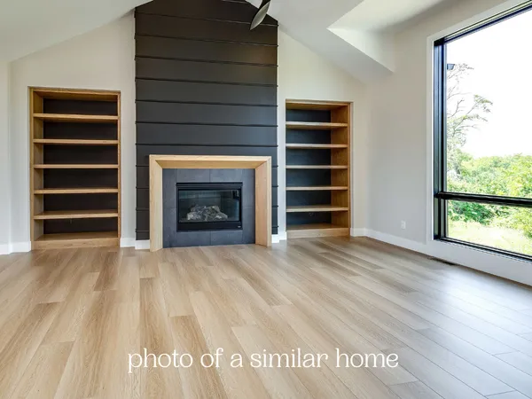 a view of an empty room with a fireplace and wooden floor